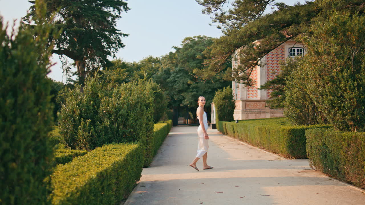 여름 저녁에 정원 골목을 가로지르는 여자. 아름다운 녹색 공원을 고 있는 소녀