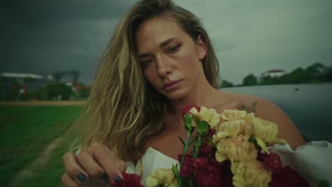 woman with flowers near a vintage car on a cloudy day
