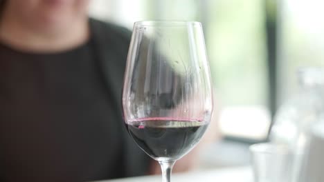 primer plano desconocido camarero mano vertiendo vino en vaso en el interior. mujer joven mano tomando vaso de vino con bebida en el interior del restaurante.