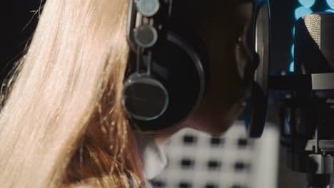 girl gazes through mic filter at audio studio. mischievous little girl engages with audio equipment in music center. kid exhibits signs of fatigue