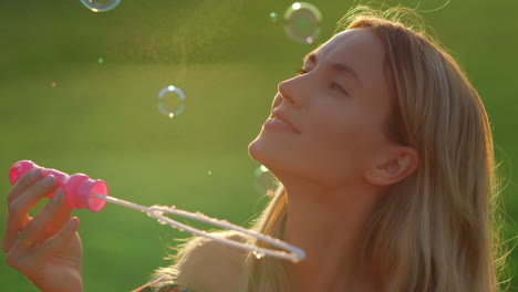 Portrait-of-beautiful-woman-blowing-soap-bubbles-in-city-park-at-summer-evening.