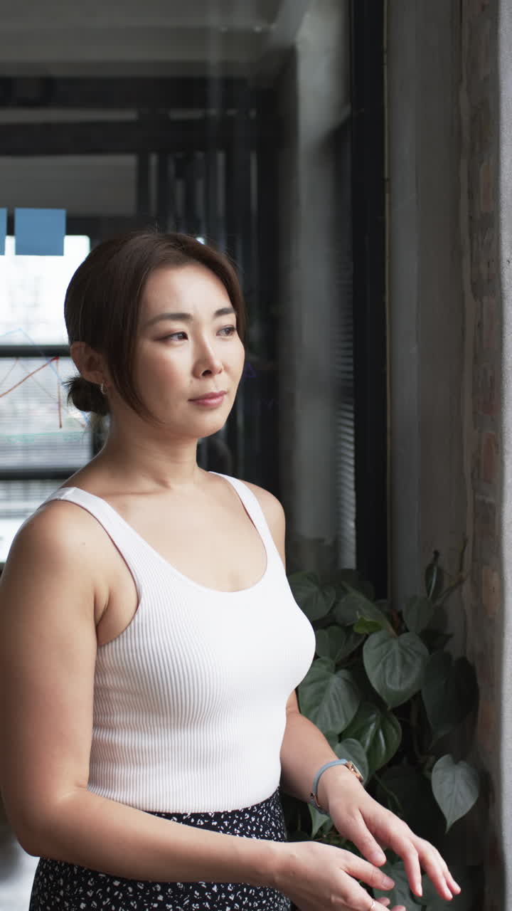 Vertical video: Standing confidently in modern office, businesswoman wearing white tank top and watc