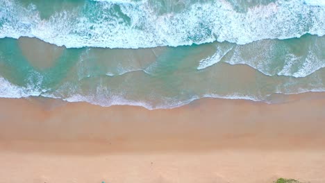 aerial top view blue waves crashing on the beach.