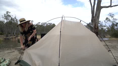 blonde woman packing up tent outdoor camping in australia