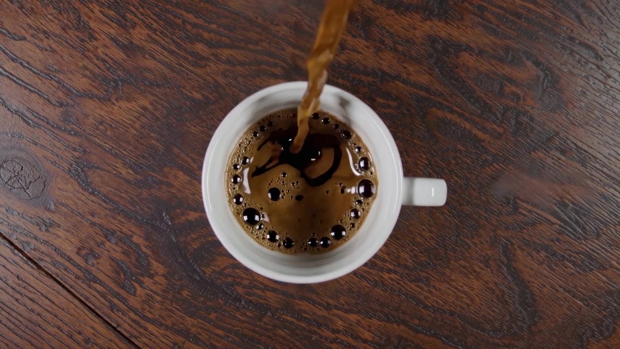 Vertiendo café humeante en una taza blanca