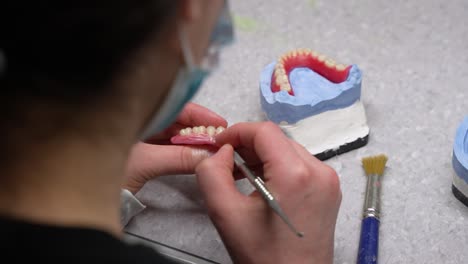fabricación de prótesis dentales y extirpación de abolladuras en encías de cera artificial con bisturí en el puesto de trabajo por un trabajador de la salud