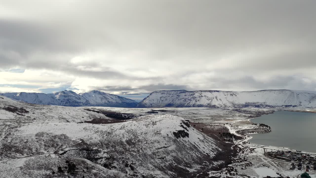 Panoramic aerial view of snow-covered mountains, Caviahue town, and lake in Neuquén, Argentina