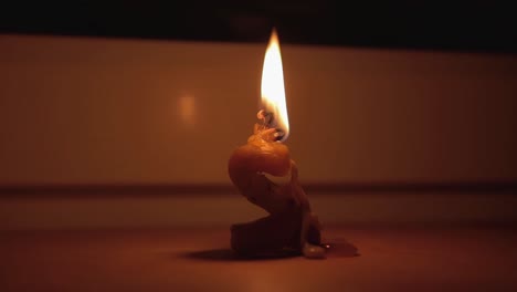 una vela deformada arde en la oscuridad