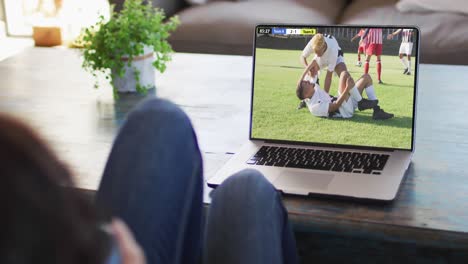 Video-Einer-Person,-Die-Auf-Der-Couch-Sitzt-Und-Sich-Ein-Fußballspiel-Auf-Dem-Laptop-Ansieht