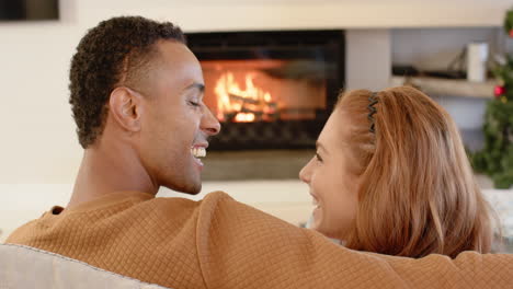 diverse couple relaxing by cozy fireplace, enjoying warm holiday moments together