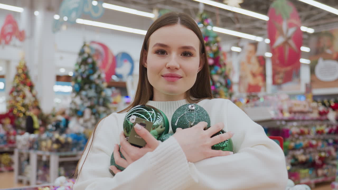 Dame met prachtige, glinsterende groene ornamenten, die hartelijk glimlacht van bewondering terwijl ze geniet van de ervaring in een decoratiewinkel, omringd door feestelijke versieringen en een vage achtergrond