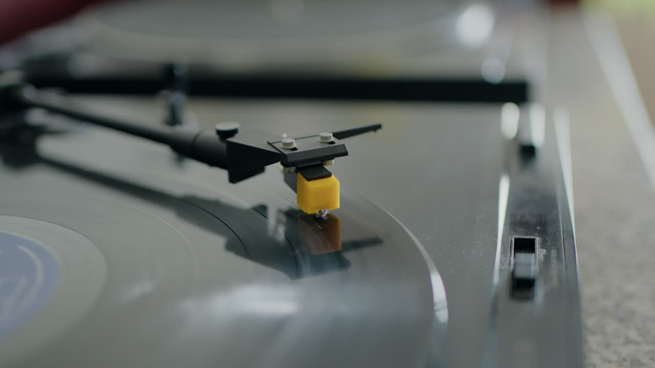 비닐 레코드에 있는 레코드 플레이어 바늘의 클로즈업으로, 사용 중인 빈티지 오디오 장비를 처합니다.