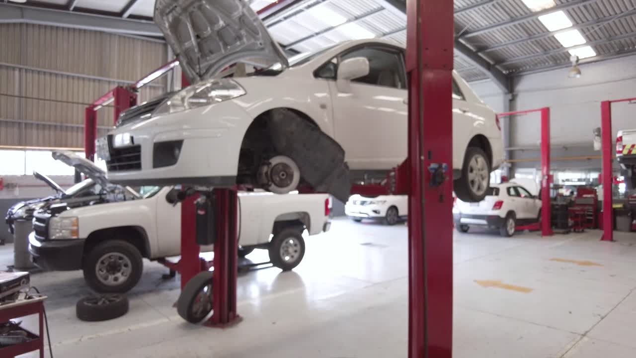 A dirty used oil drum at a workshop station garage at mexico latin-america with a white car and a white truck in the background