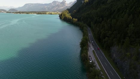 cars driving on a scenic lakeside road with mountains in the background in mondsee, austria