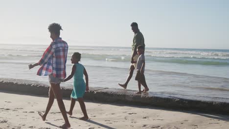 african american family holding hands walking together on the beach