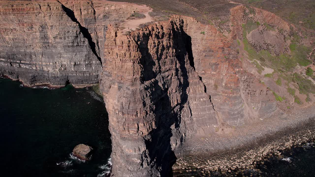 Enorme scogliera sedimentaria con stratificazione orizzontale visibile, frattura tettonica e base di abrasione marina lungo la costa atlantica di Vila Nova de Mil Fontes Odemira Alentejo Portogallo, ripresa con drone in orbita