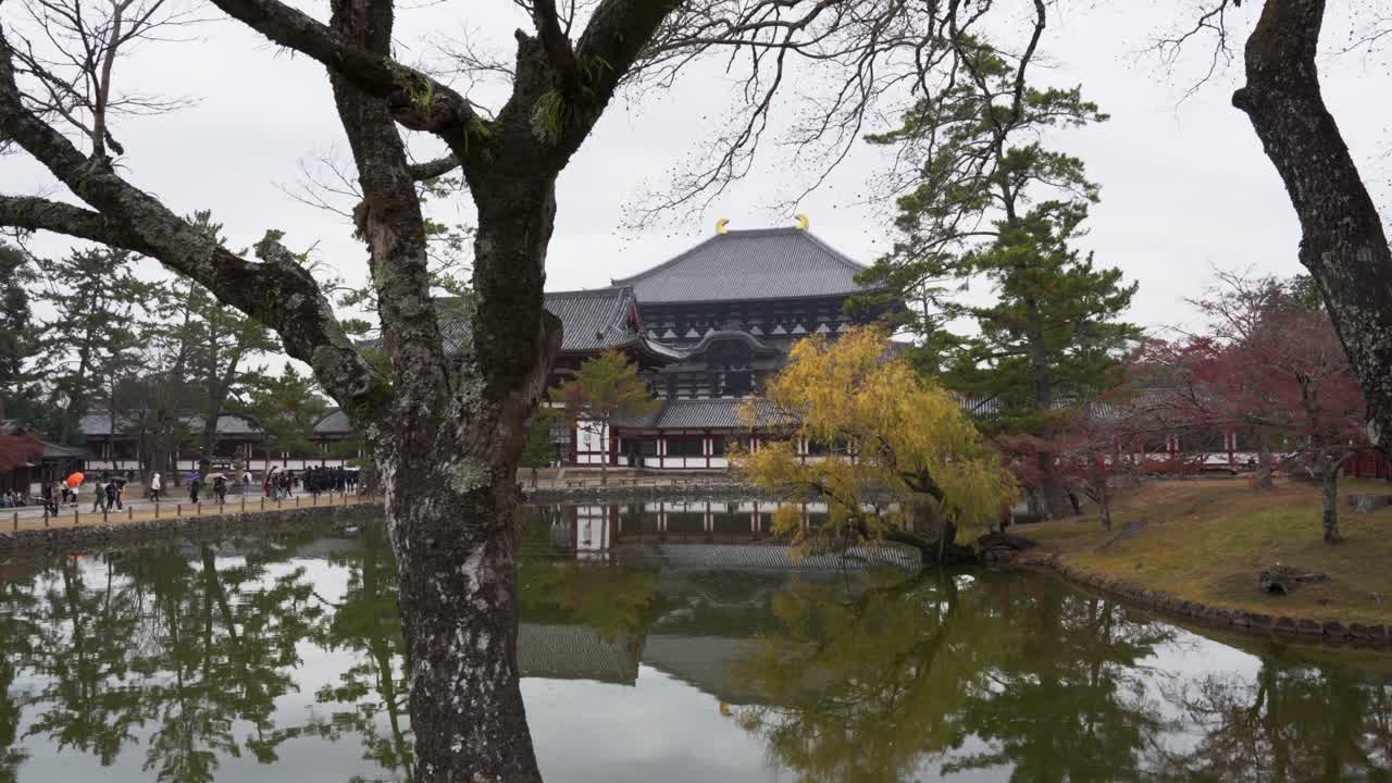 estanque reflectante con árboles de otoño enmarcando el templo de tōdai-ji, nara, japón, cielo nublado