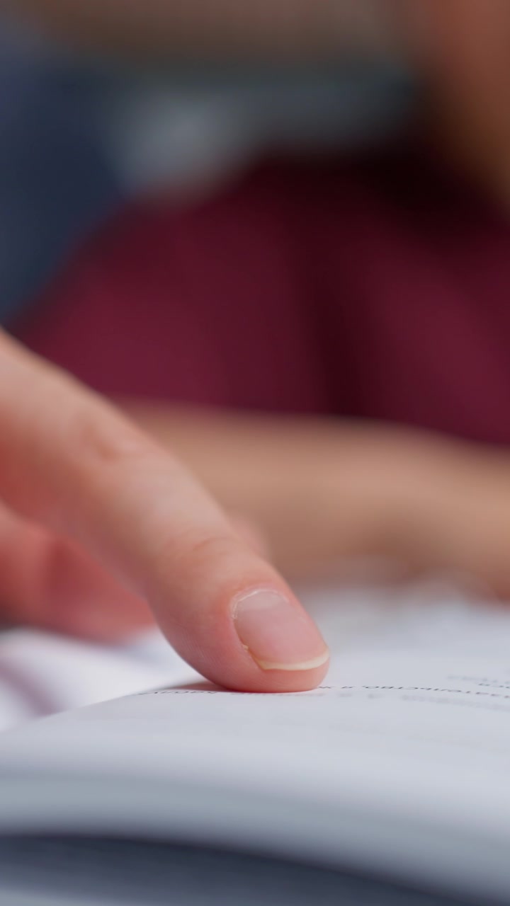 Primo piano di una mano che legge e scrive su carta.