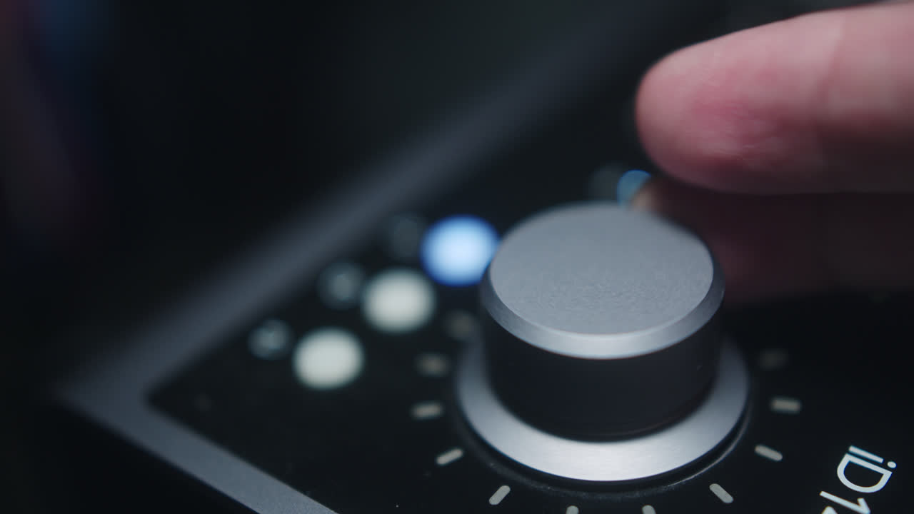 Beautiful slow motion shot of a sound interface being manipulated by a man's hand as he moves the volume knob on an Audient ID 14 interface in his home studio