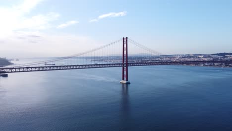 Drone-Volando-Lateralmente-Sobre-El-Tejo-De-Lisboa-Portugal-Europa-Con-El-Poderoso-Puente-Parecido-A-La-Puerta-Dorada