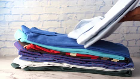 Men-hand-putting-shirts-on-table