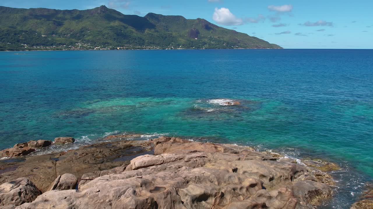Reveal  drone shot of granite rock boulders and calm sea water on the sunset beach, Mahe Seychelles, slow motion