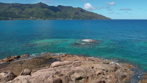 reveal  drone shot of granite rock boulders and calm sea water on the sunset beach, mahe seychelles, slow motion