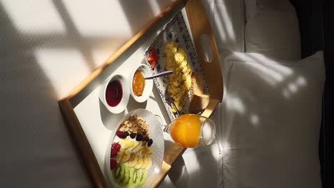 vertical view of healthy room service breakfast tray on sunny hotel room bed