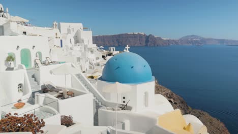 Vertical-pan-over-white-and-blue-church-with-seaview-background-in-Santorini,-Greece