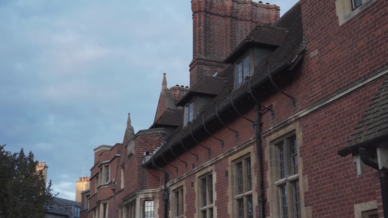 Elegant and clean building with red bricks in the city centre of Cambridge, England. Tree with green leaves