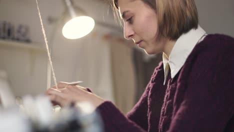 Woman-using-tool-for-pulling-thread-in-weaving-machine