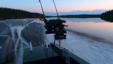 side view of a fishing boat speeding on a calm lake with a colourful sunset view