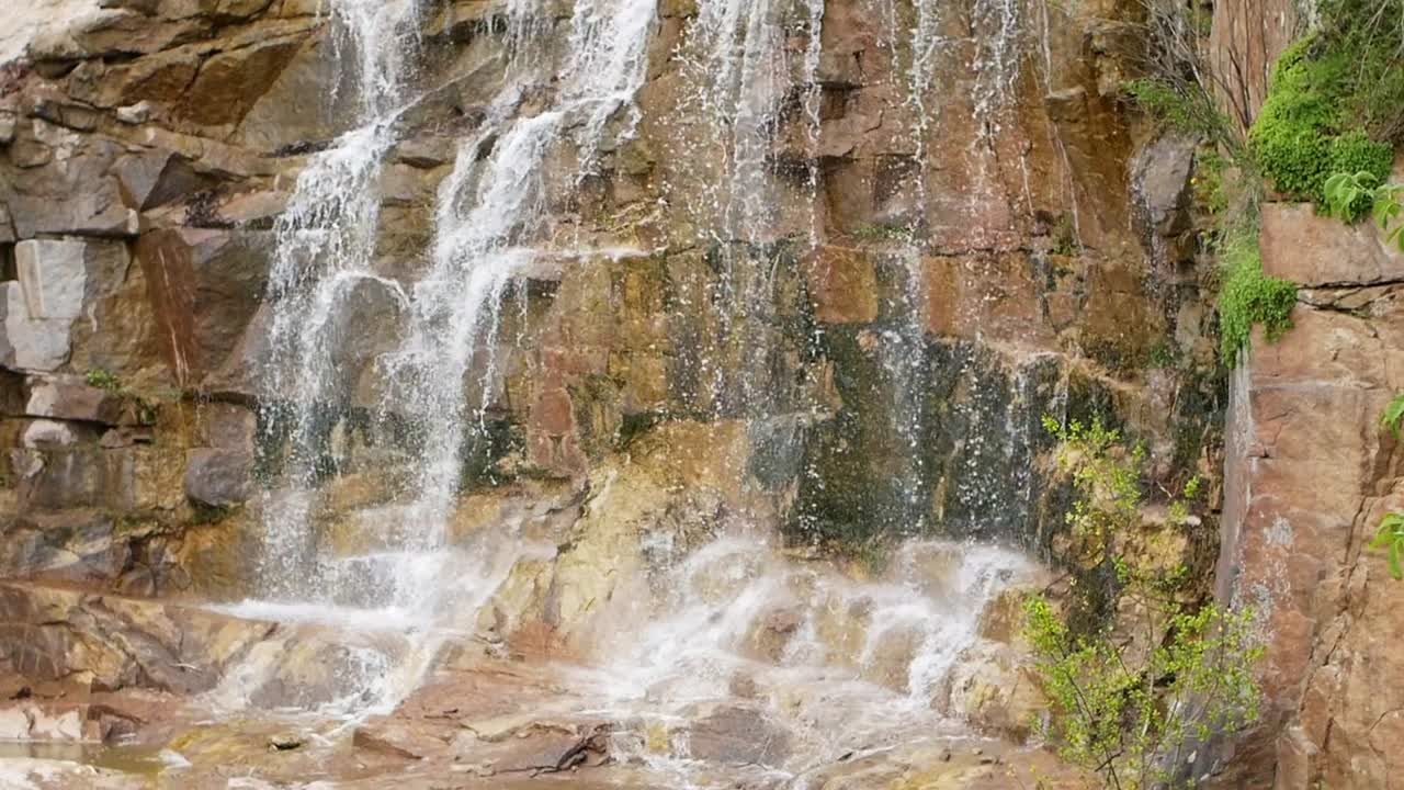 hermosa cascada desde un acantilado en el bosque. 4k video de agua que fluye, arroyo que fluye entre las piedras. arroyo en el bosque