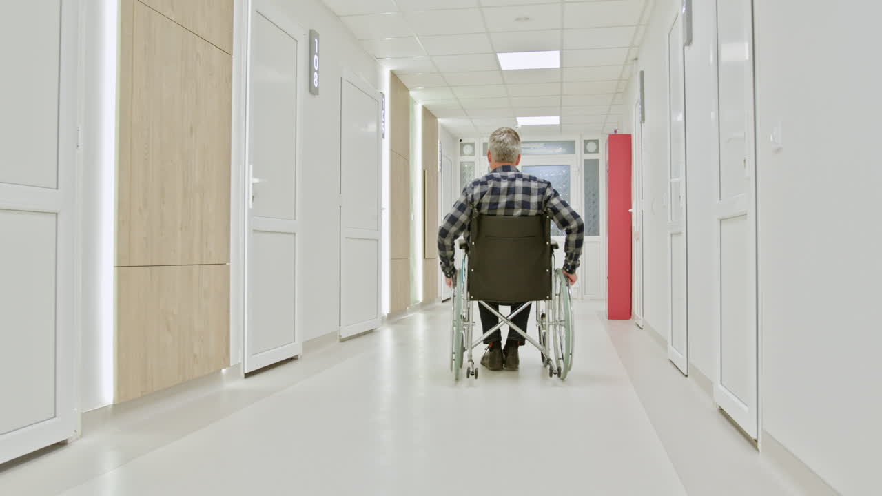 hombre en silla de ruedas en el pasillo del hospital