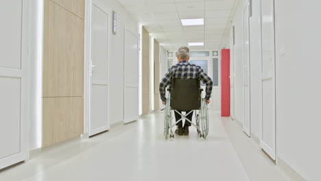 hombre en silla de ruedas en el pasillo del hospital