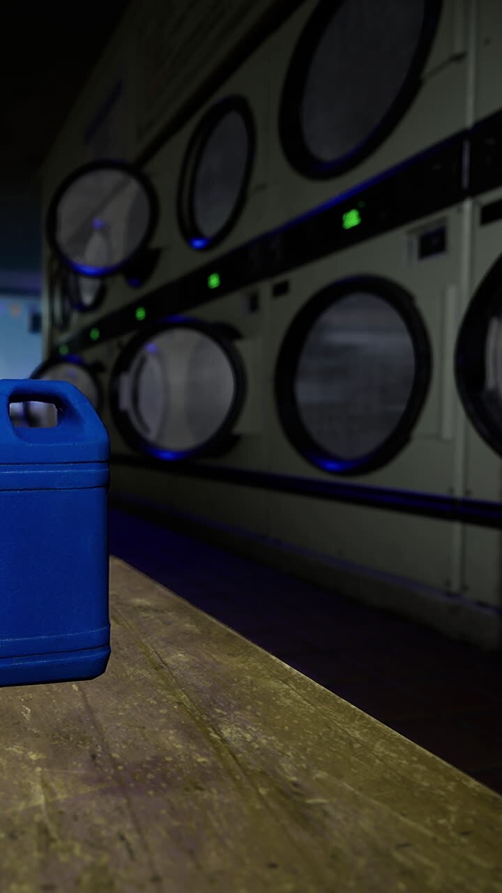 Blue container sits on a table in a laundromat with washing machines behind