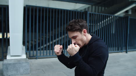 un chico guapo practicando beats al aire libre. un joven entrenando puñetazos de boxeo