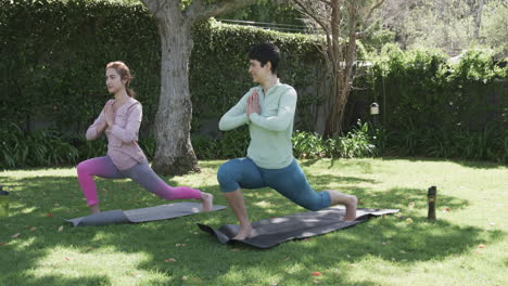 Happy-caucasian-lesbian-couple-practising-yoga-in-sunny-garden,-slow-motion