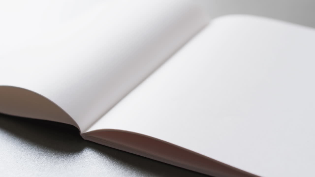 Close up of open blank book with copy space on gray background in slow motion