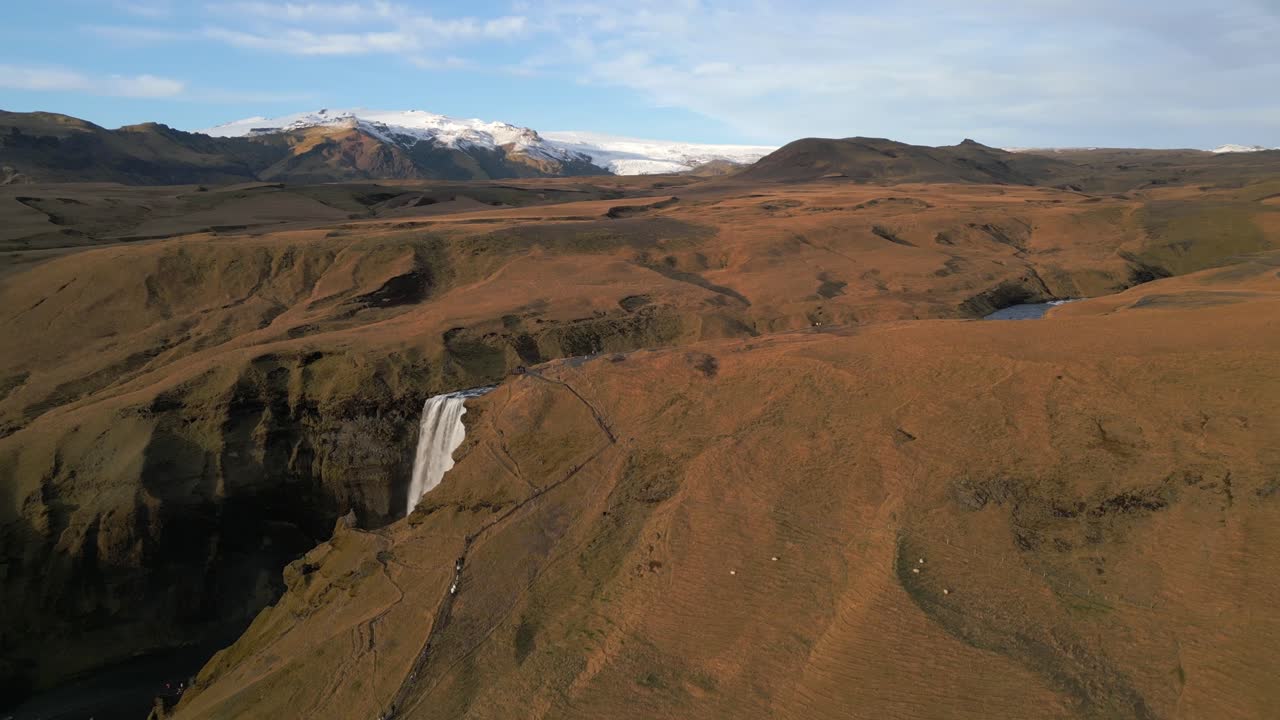 montañas nevadas más allá de la espectacular cascada de skogafoss
