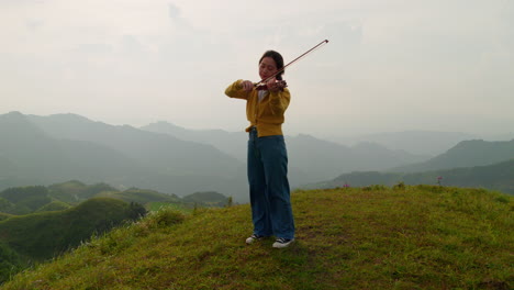 female musician plays the violin in a misty mountaintop paradise