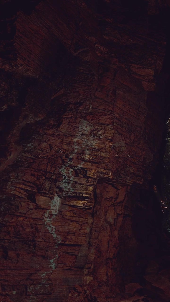 Natural rock formation near a cave with trees and light breaking through