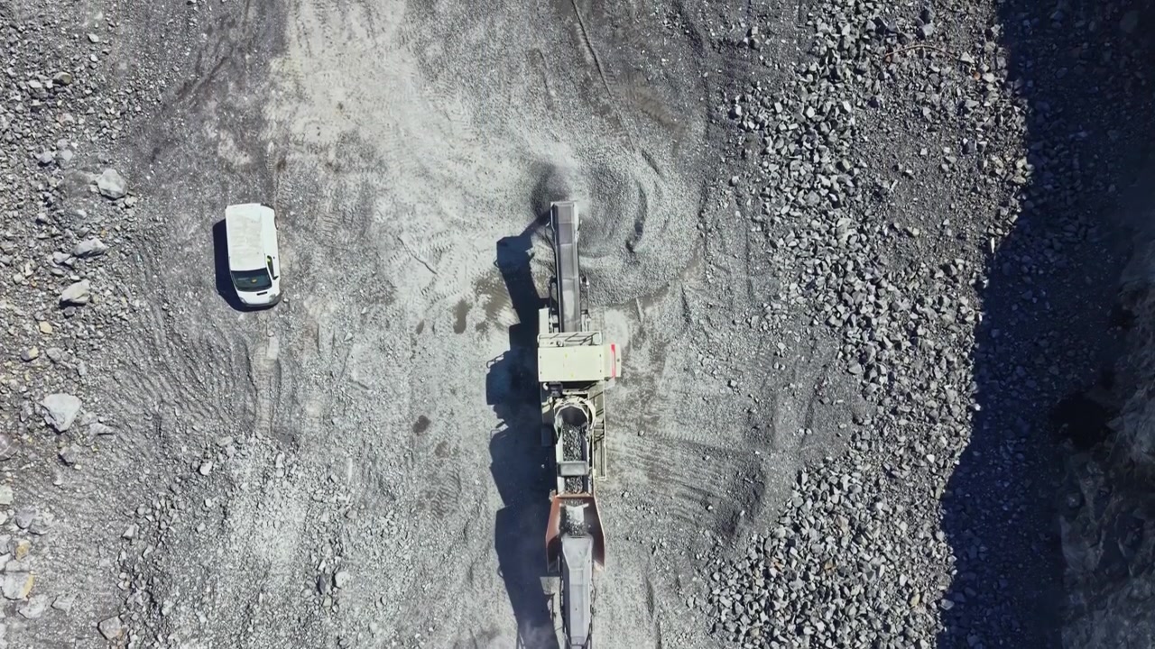 Granite quarry machinery operates to extract stones and rocks during daylight in a busy construction site