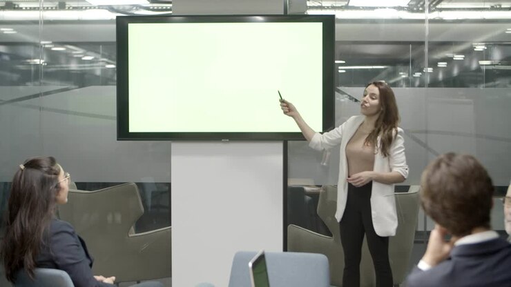 Oradora concentrada hablando mientras está de pie cerca de la pantalla