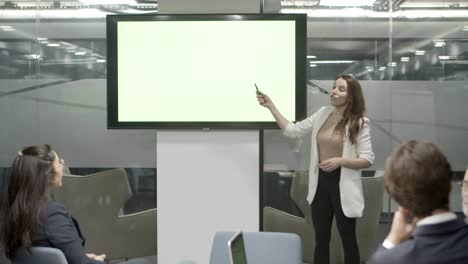 Concentrated-female-speaker-talking-while-standing-near-display