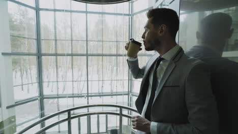 businessman drinking coffee in elevator