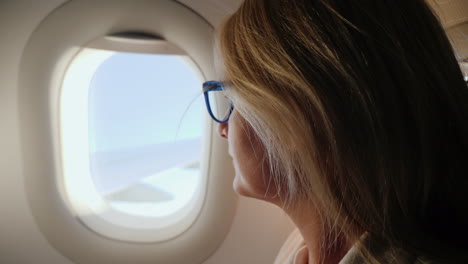 Geschäftsfrau-Mit-Brille,-Die-In-Einem-Flugzeug-Fliegt-Und-Aus-Dem-Fenster-Schaut