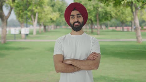 Happy-Sikh-Indian-man-standing-crossed-hands-in-park