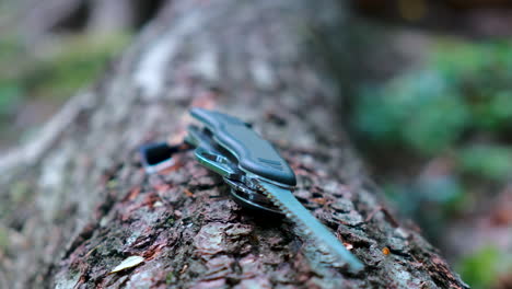 swiss multi-purpose survival and outdoor knife with an extended saw blade on a tree trunk in the forest