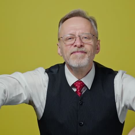 excited mature man with dollars in hands. happy elderly man is waving many dollar bills isolated on yellow background. slow motion. positive emotions.